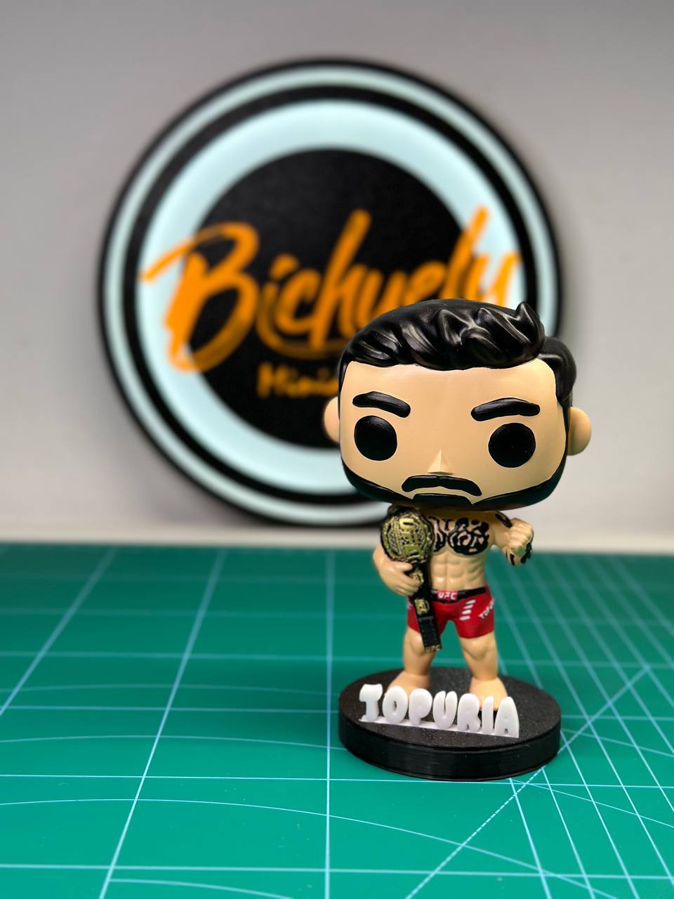 Figura coleccionable de Ilia Topuria, campeón de UFC, pintada a mano, con base personalizada, inspirada en el mundo de las MMA.
